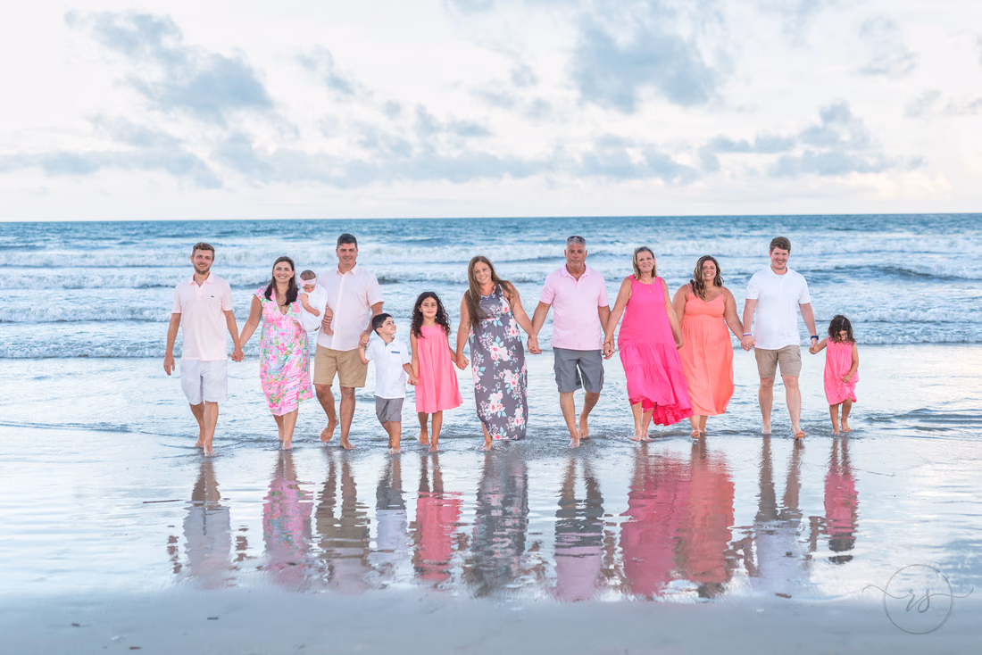 Large family in pink and white walking along the wet sand at Ocean Isle Beach, NC