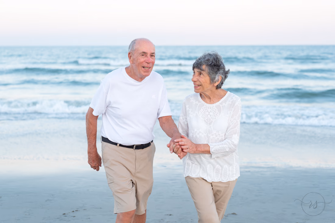 Grandparents holding hands walking down the beach at Huntington Beach State Park