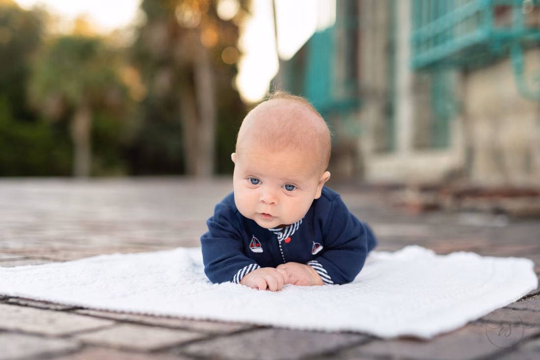 Baby boy lifting his head on a white blanket by Atalaya Castle at Huntington Beach State Park