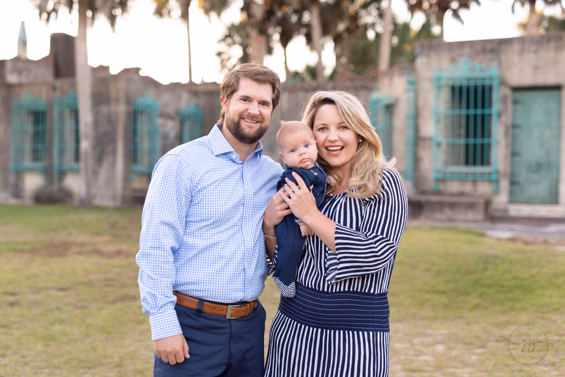 Parents stand in the courtyard of Atalaya Castle holding their baby boy at Huntington Beach State Park