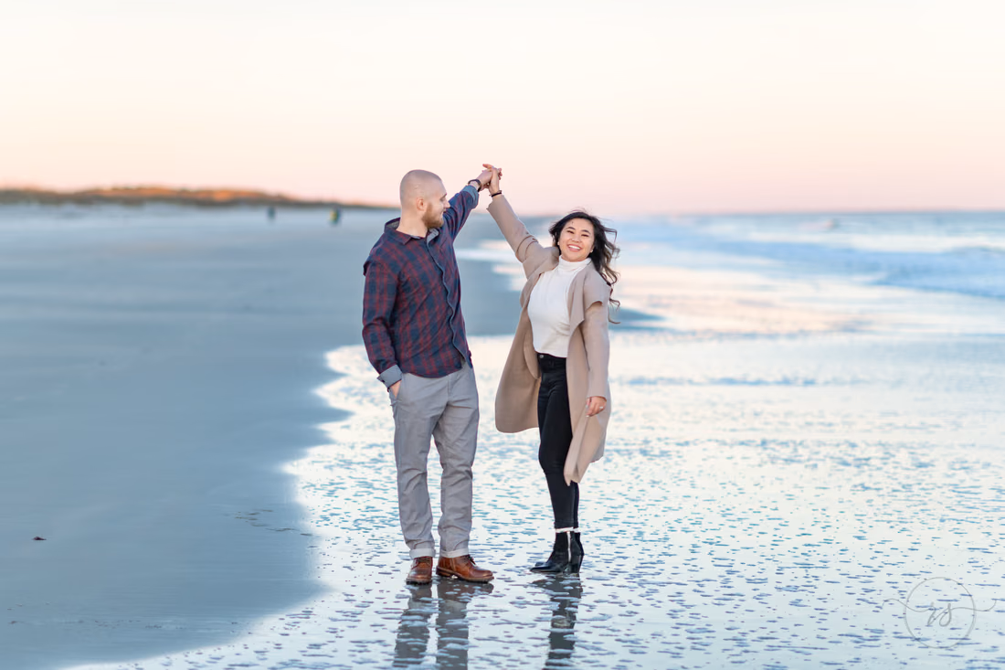 Couple twirling at the water's edge at sunset at Huntington Beach State Park