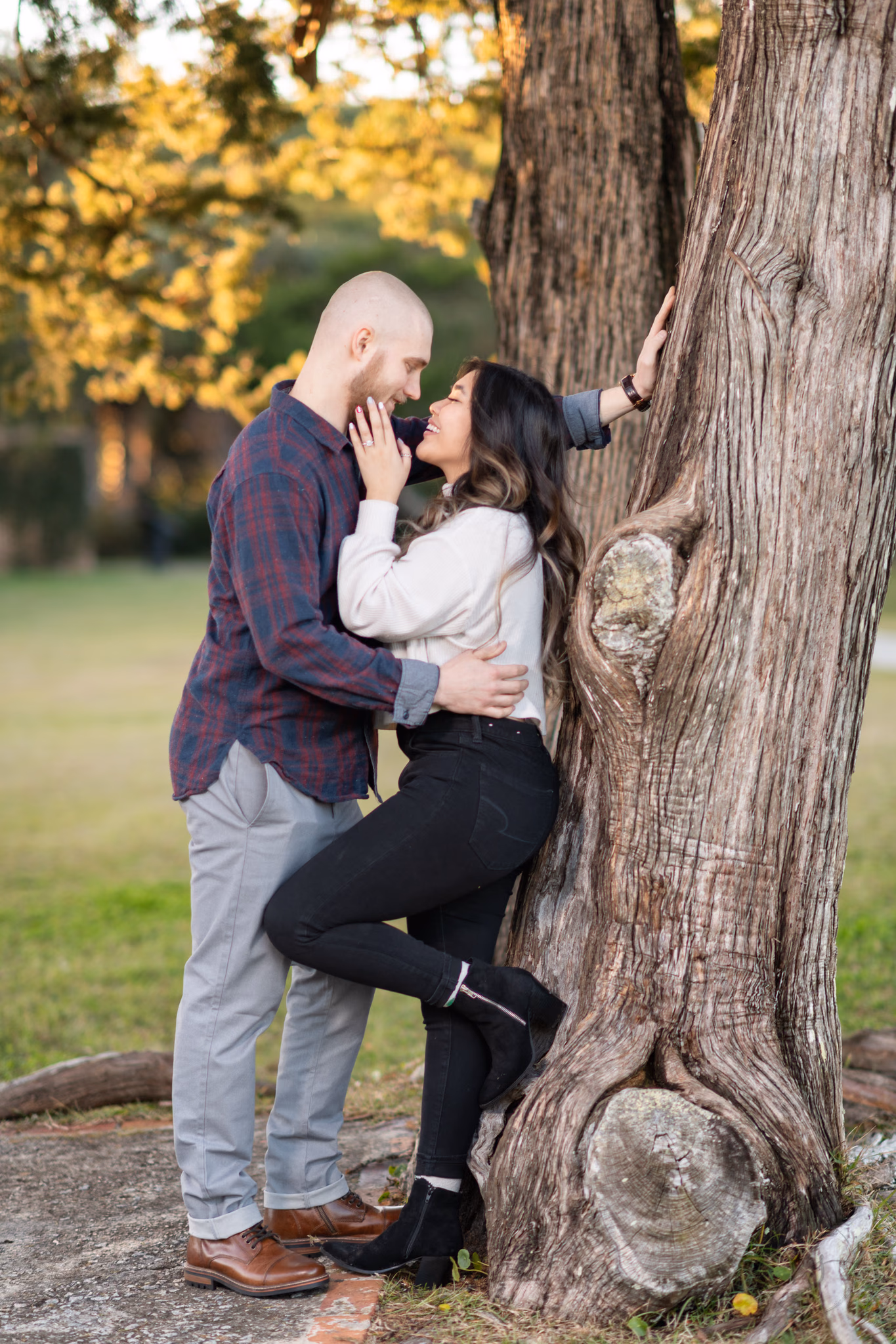 Couple kiss while leaning against an old oak trunk at Huntington Beach State Park