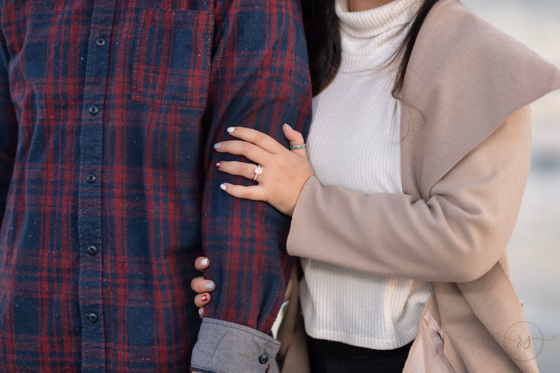 Close-up of her engagement ring as she holds his arm at Huntington Beach State Park