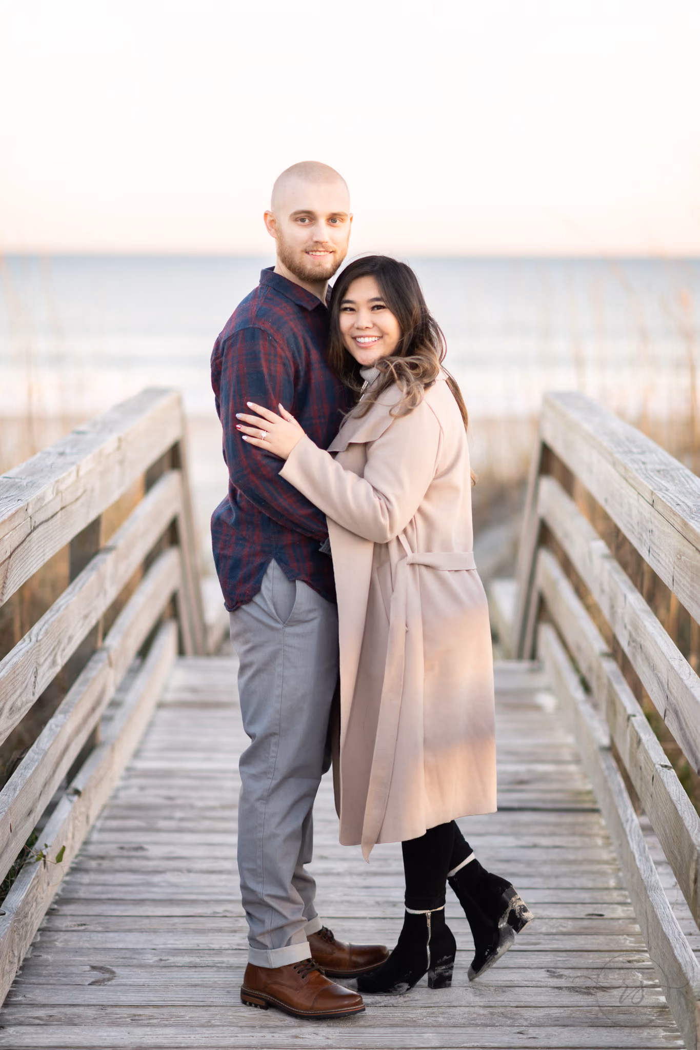 Couple smiling on the wooden dune walkway with the ocean behind them at Huntington Beach State Park