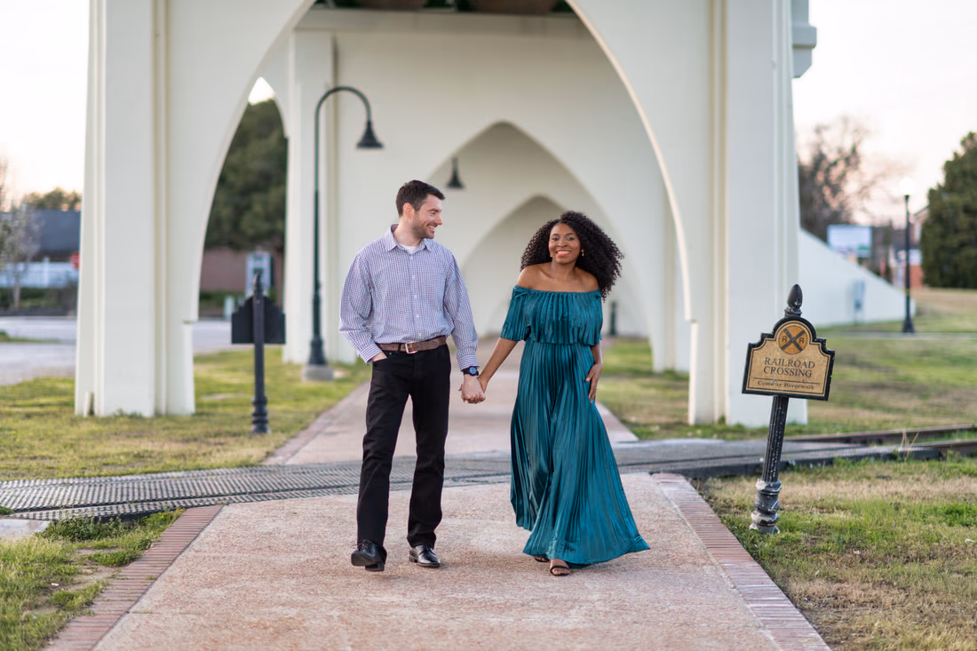 Couple walking hand in hand under the arches of the old Conway bridge at the Conway Riverwalk