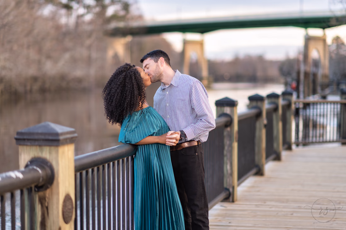 Couple kissing while leaning on the boardwalk railing at the Conway Riverwalk