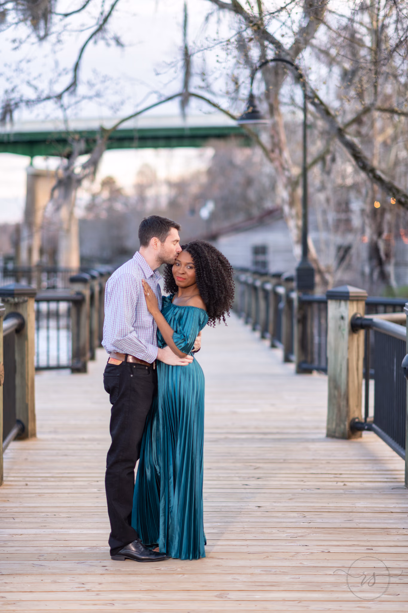 Husband kissing wife on the forehead framed by tree branches - Conway Riverwalk