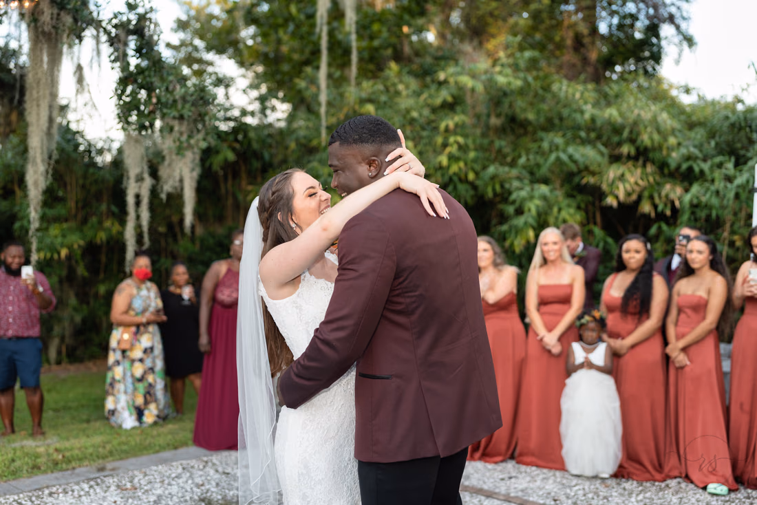 Bride wraps her arms around the groom's neck during their first dance at Magnolia Plantation