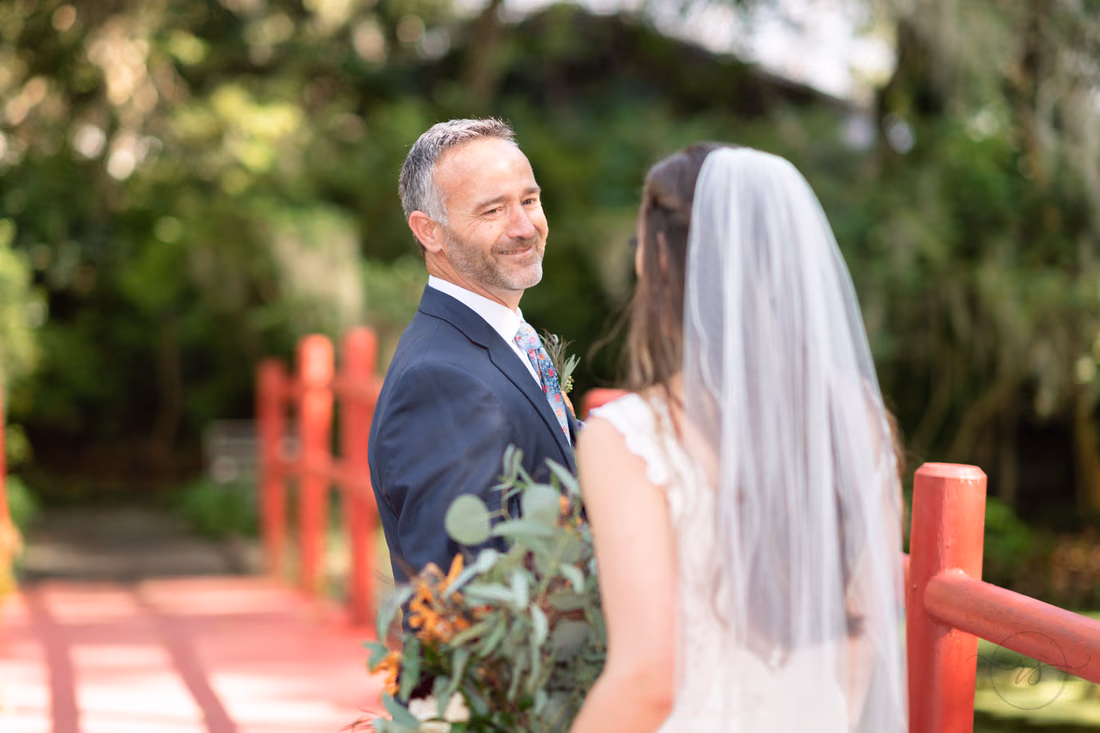 Father smiles as he sees the bride for the first time by the red bridge at Magnolia Plantation