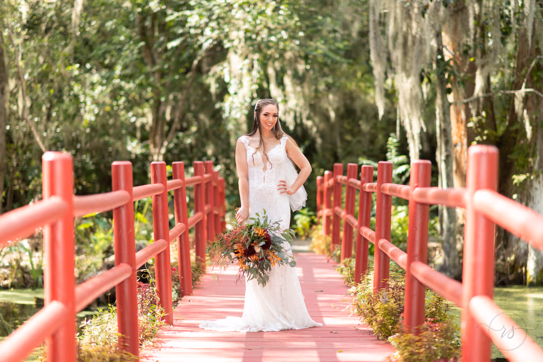 Bride poses with a hand on her hip on the red bridge at Magnolia Plantation
