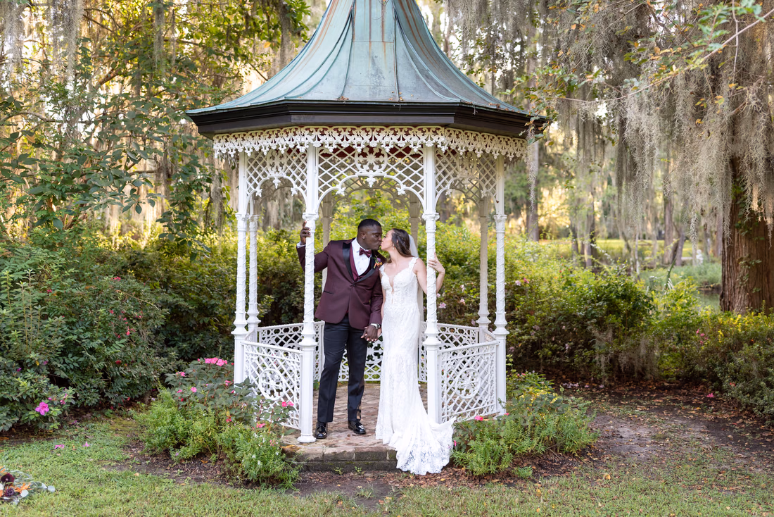 Groom kisses the bride inside the white gazebo at Magnolia Plantation