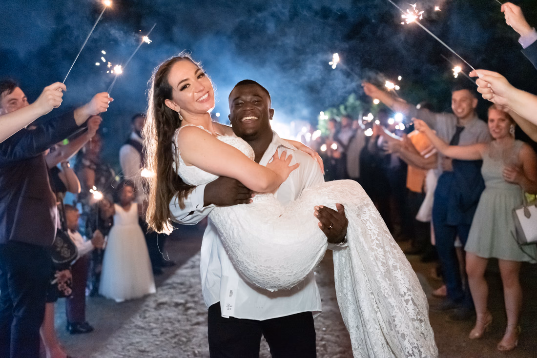 Groom carries the bride through the sparklers at Magnolia Plantation
