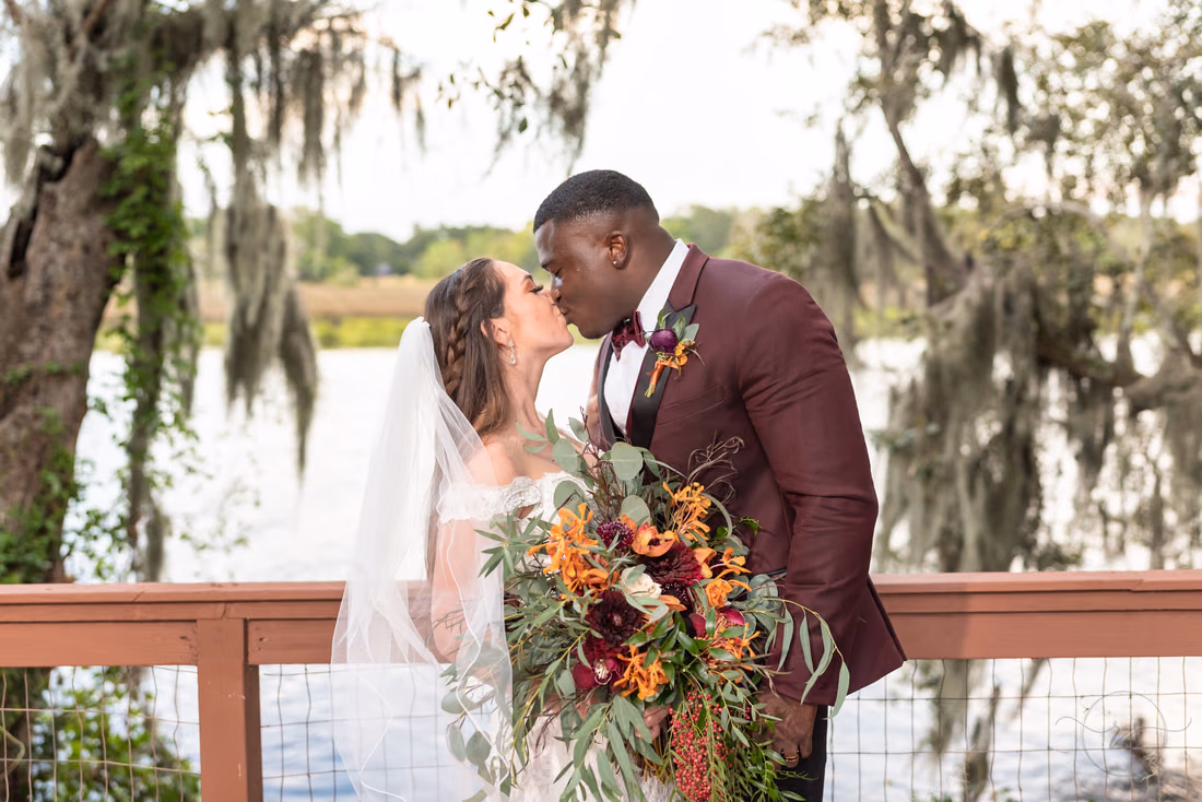 Bride and groom kiss on the dock at the Carriage House at Magnolia Plantation