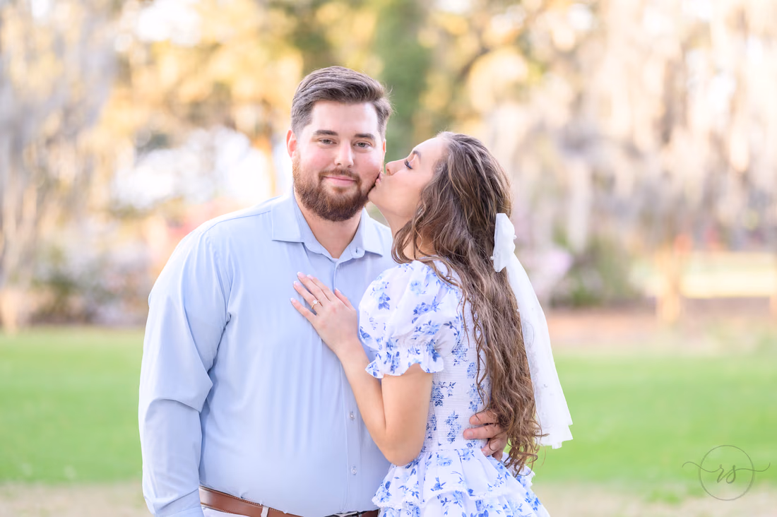 She kisses his cheek in a close portrait under the oaks at Caledonia Golf and Fish Club