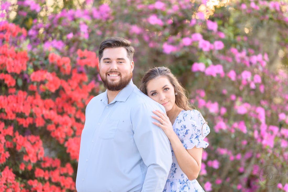 She rests her head on his shoulder in front of blooming azaleas at Caledonia Golf and Fish Club