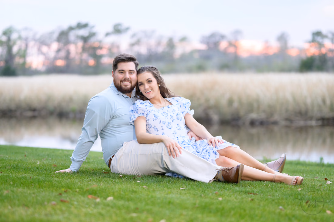 Couple sitting together in the grass by the river at sunset at Caledonia Golf and Fish Club