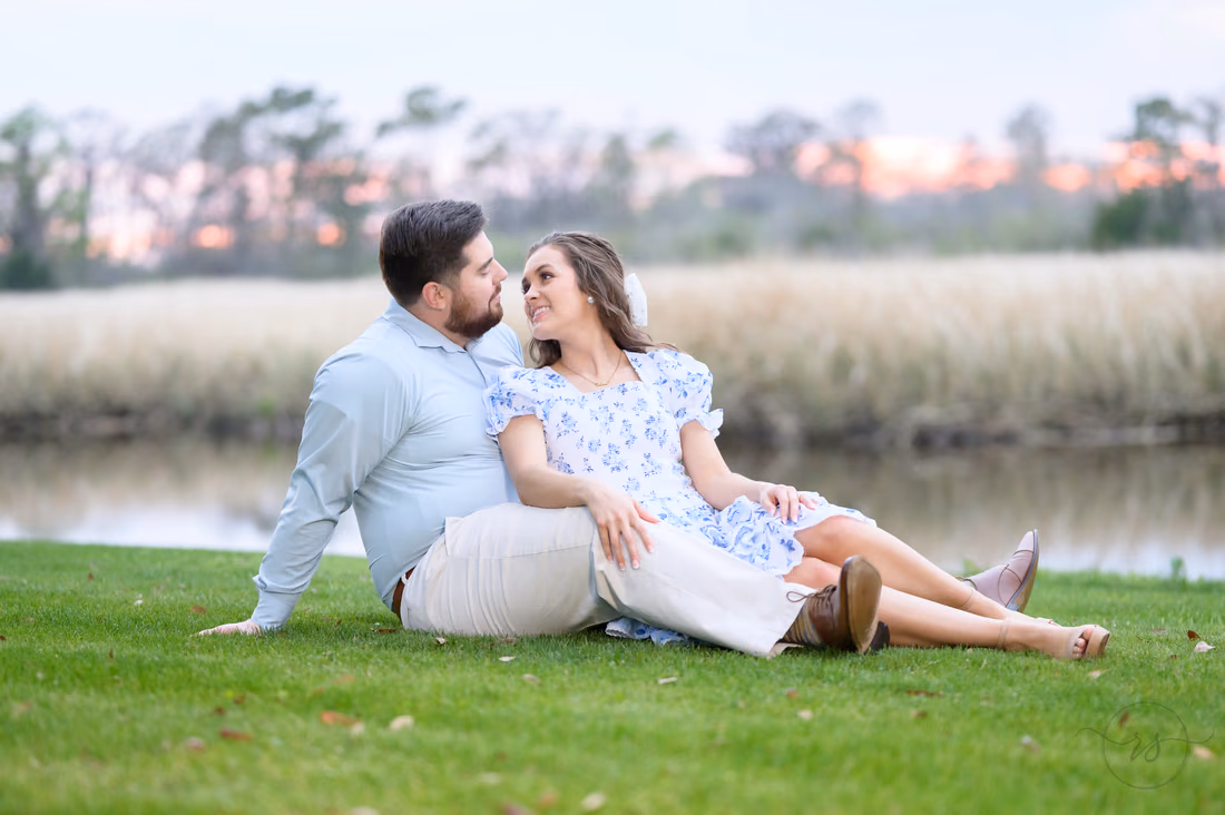 Couple reclining in the grass and gazing at each other by the river at Caledonia Golf and Fish Club