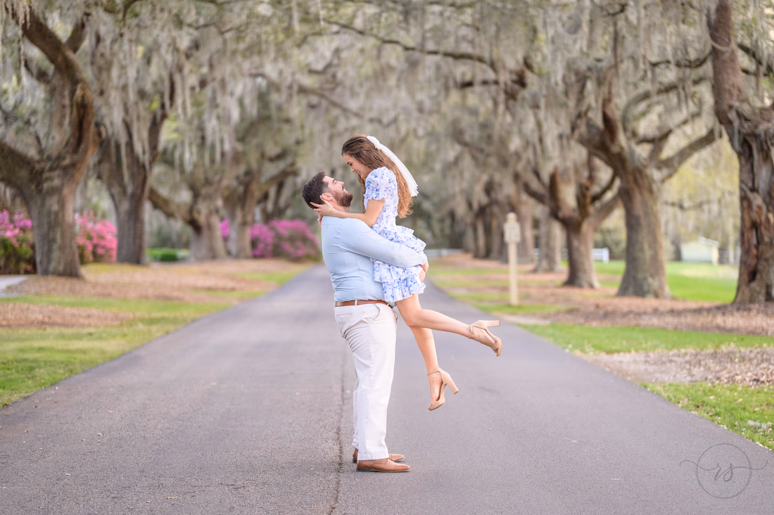He lifts her up as she looks down at him on the oak-lined road at Caledonia Golf and Fish Club