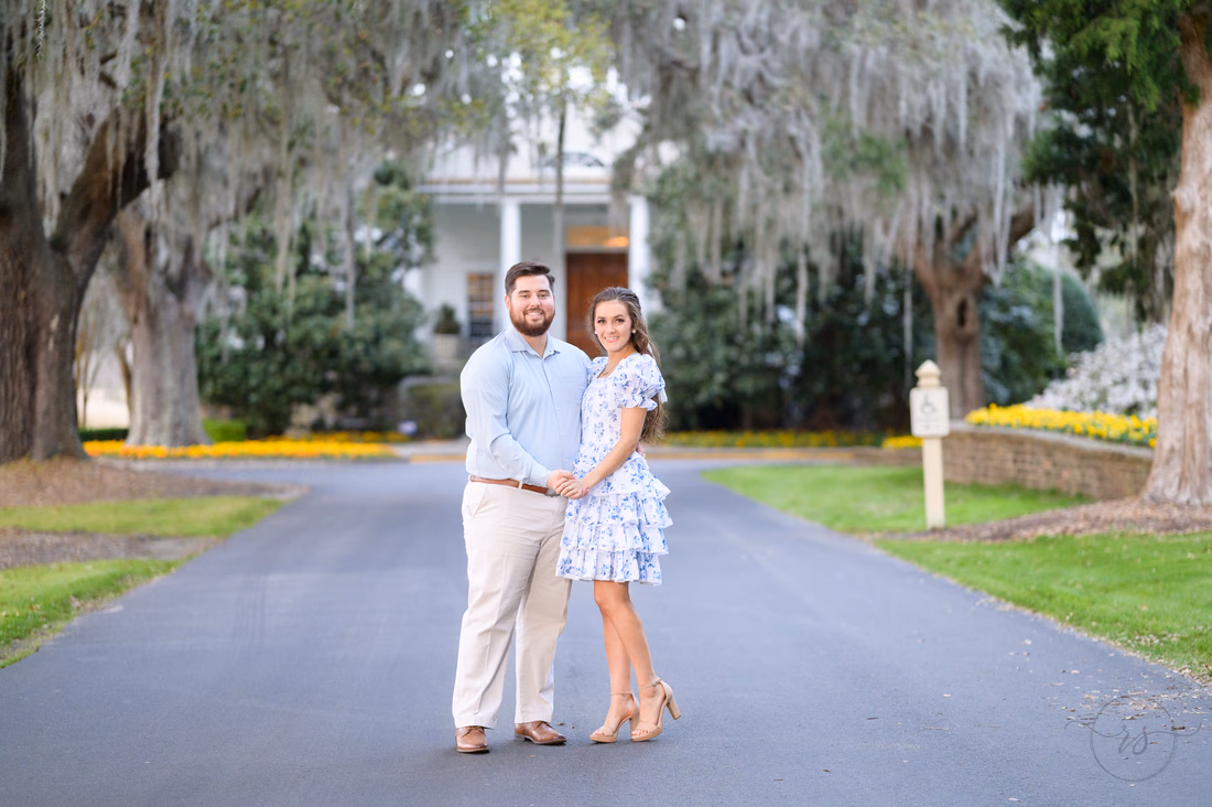 Couple standing together on the drive in front of the white clubhouse at Caledonia Golf and Fish Club