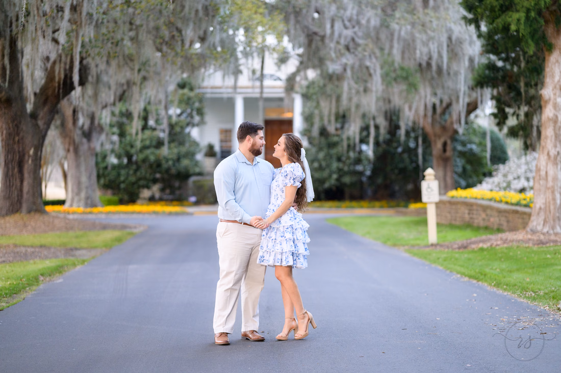 Couple embracing on the drive below the moss-draped oaks and clubhouse at Caledonia Golf and Fish Club