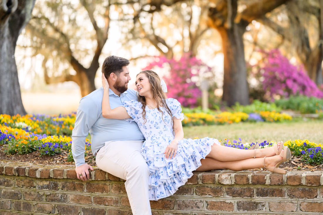 Couple lounging on a brick flower planter in front of spring blooms at Caledonia Golf and Fish Club