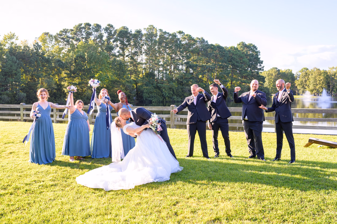 Groom dipping the bride for a kiss as the wedding party cheers - The Pavilion at Pepper Plantation