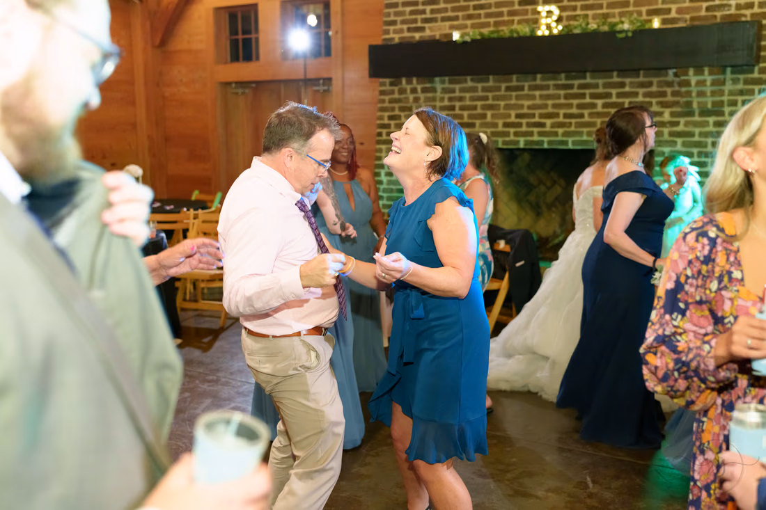 Guests laughing and dancing by the brick fireplace - The Pavilion at Pepper Plantation