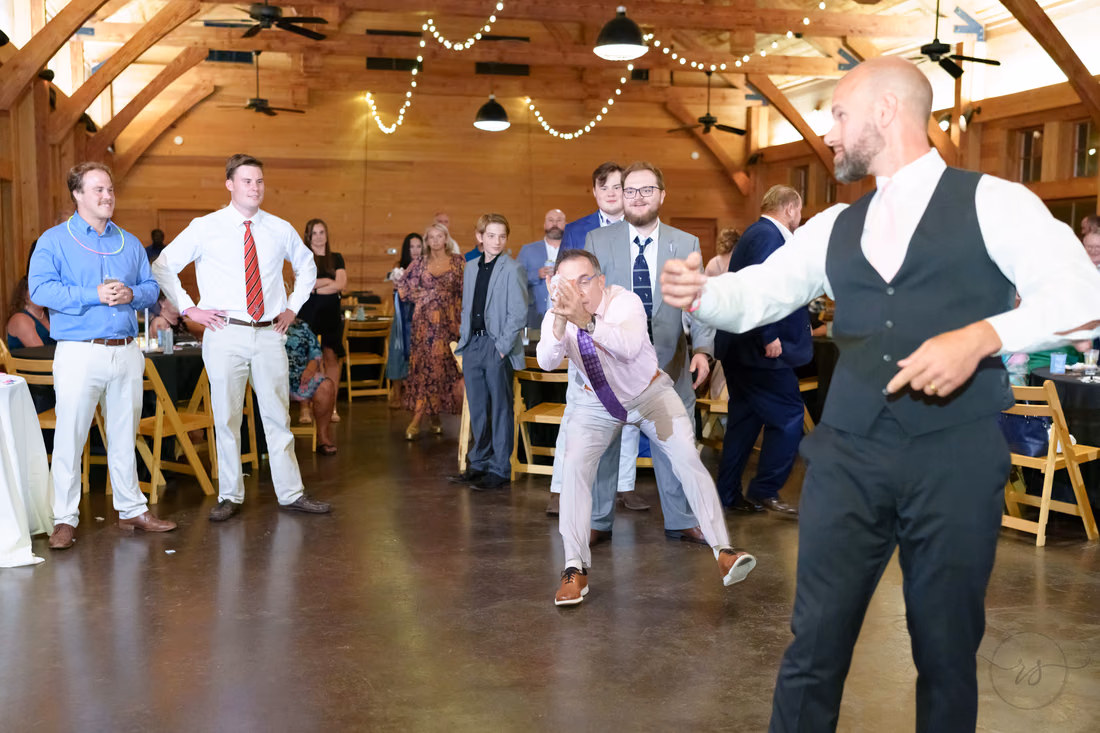 Groom pointing at a guest as the men line up for the garter toss - The Pavilion at Pepper Plantation