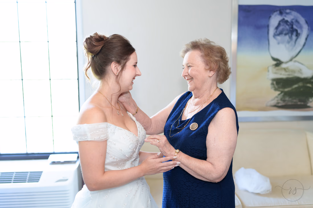 Bride and her grandmother laughing together after the necklace is on - Hotel Indigo