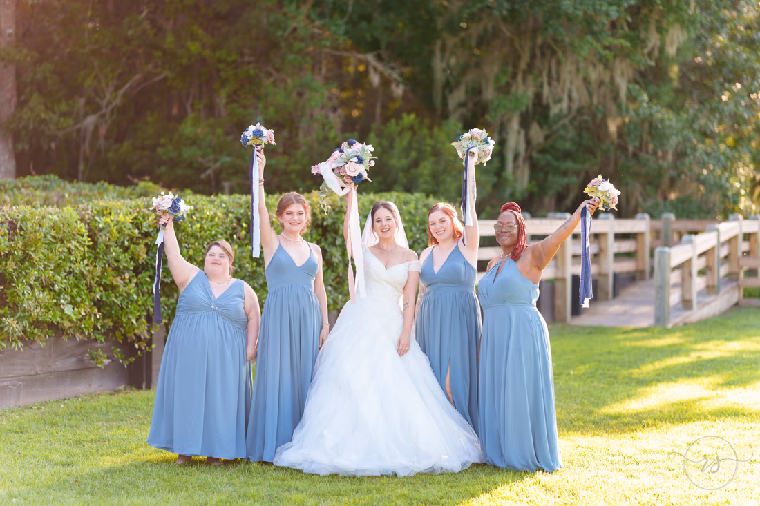 Bride and bridesmaids raising their bouquets in the air - The Pavilion at Pepper Plantation