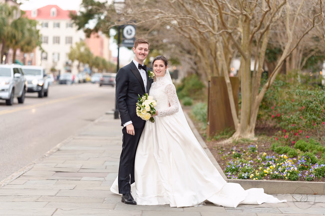Bride and groom smiling by the street next to the park - Marion Square Charleston