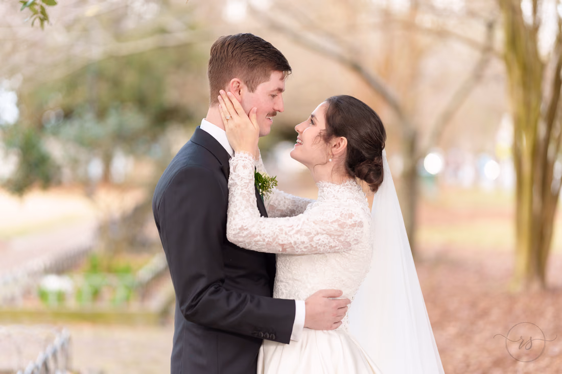 Bride holding the groom's face as they smile at each other - Marion Square Charleston