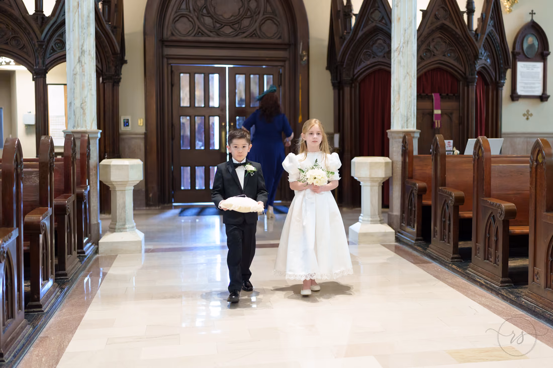 Ring bearer and flower girl walking up the aisle toward the camera - Cathedral of Saint John Charleston