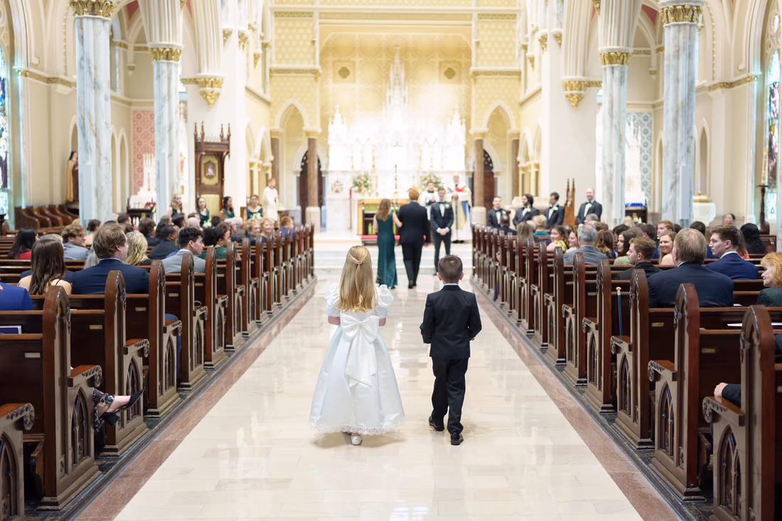Ring bearer and flower girl walking down the long aisle toward the altar - Cathedral of Saint John Charleston
