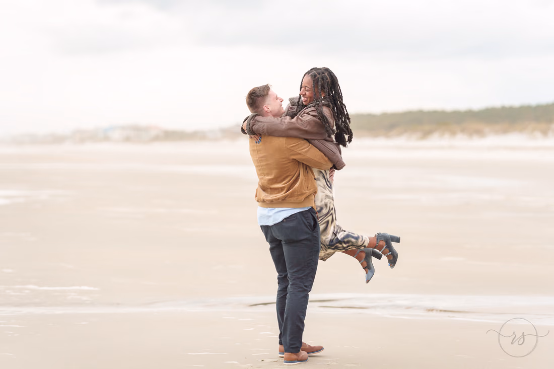 She jumps into his arms on a cloudy winter beach - Huntington Beach State Park