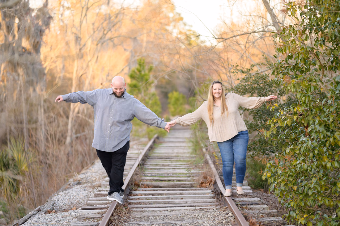 Couple holding hands and balancing on the old train tracks - Conway Riverwalk