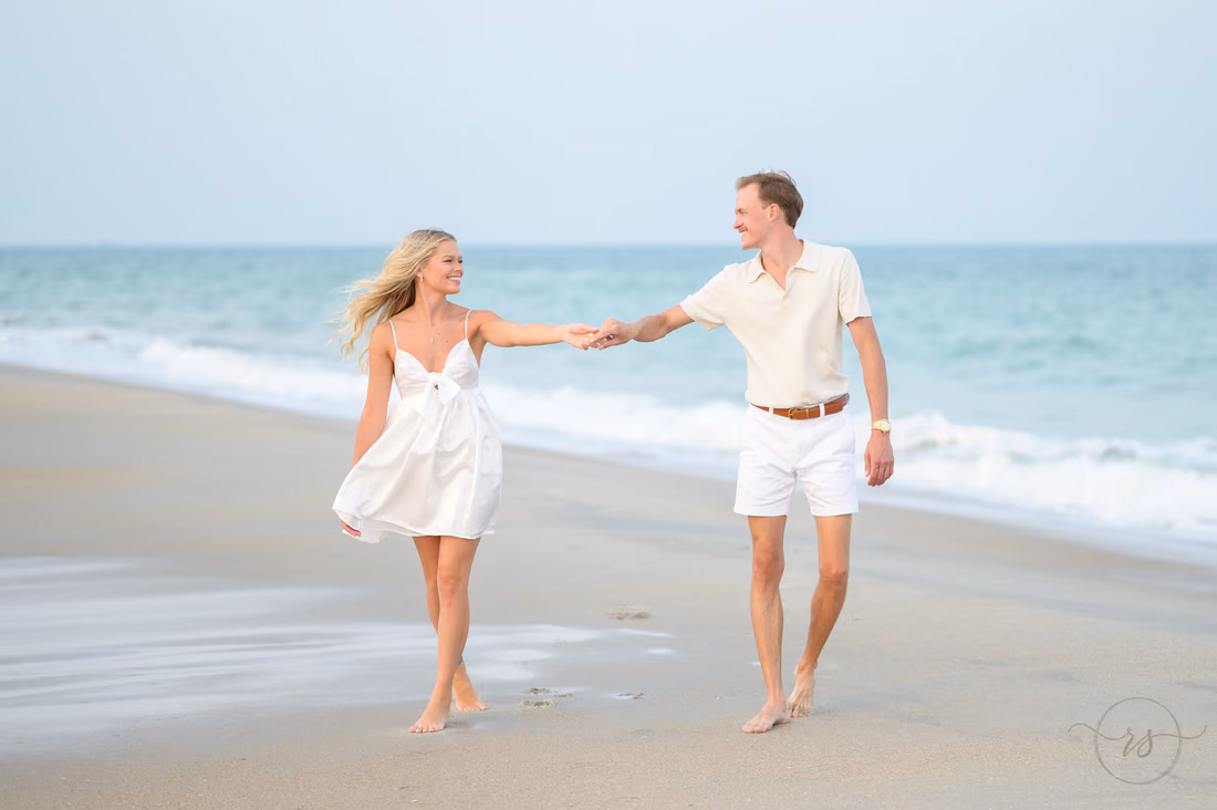 Couple holding hands as they walk along the beach - Huntington Beach State Park