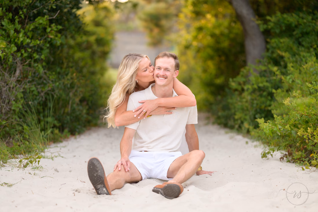 She kisses his cheek as they sit on the beach path - Huntington Beach State Park