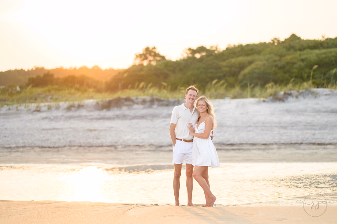 Couple standing together at the water's edge at sunset - Huntington Beach State Park