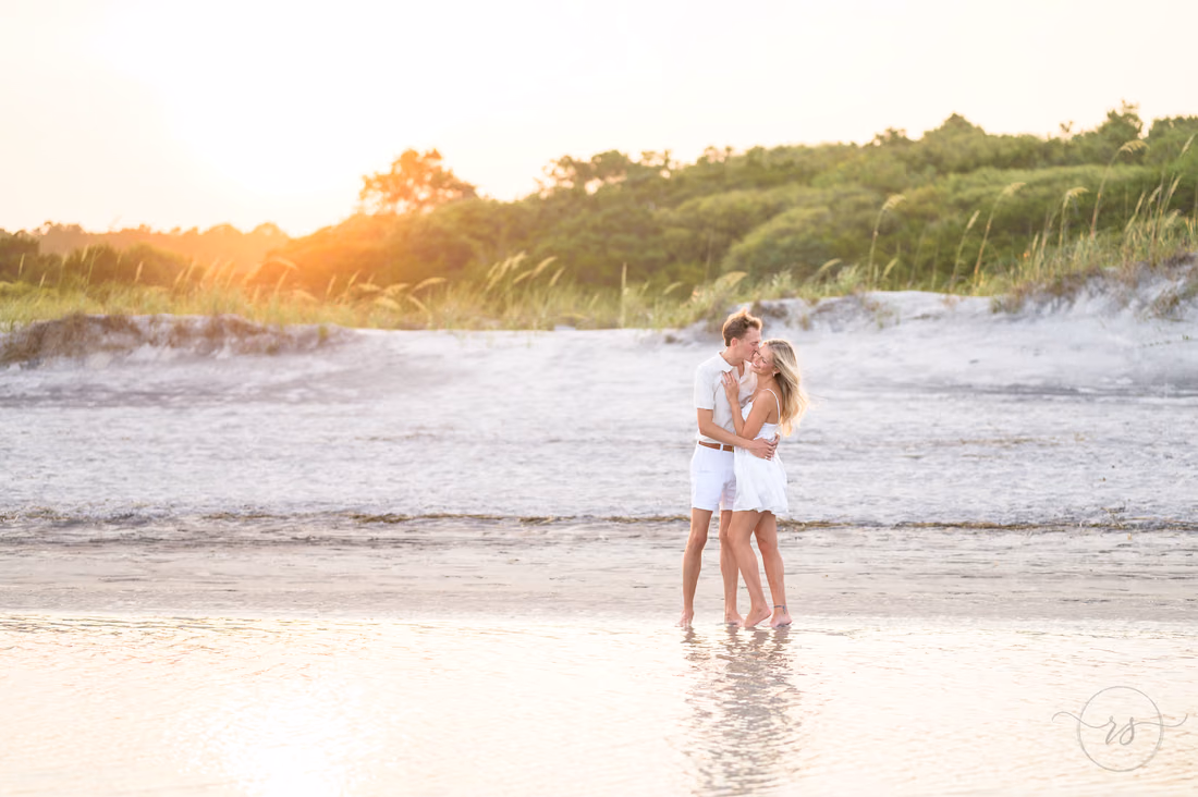 Couple kissing in the shallow water as the sun sets over the dunes - Huntington Beach State Park