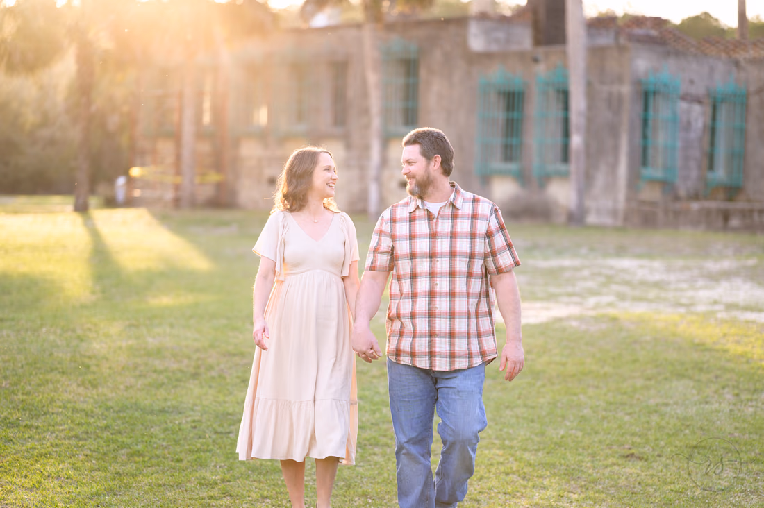 Couple walking hand in hand across the lawn at Atalaya Castle in golden light - Huntington Beach State Park
