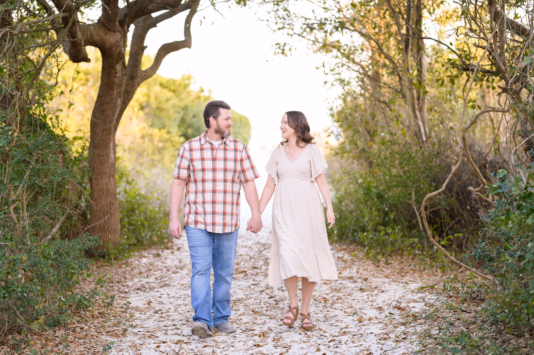 Couple walking hand in hand on the sandy path to the beach - Huntington Beach State Park