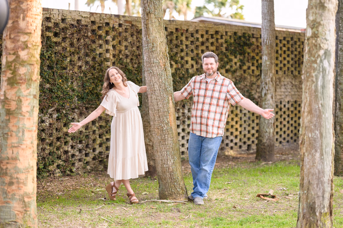 Couple posing playfully by the trees and lattice brick wall at Atalaya Castle - Huntington Beach State Park
