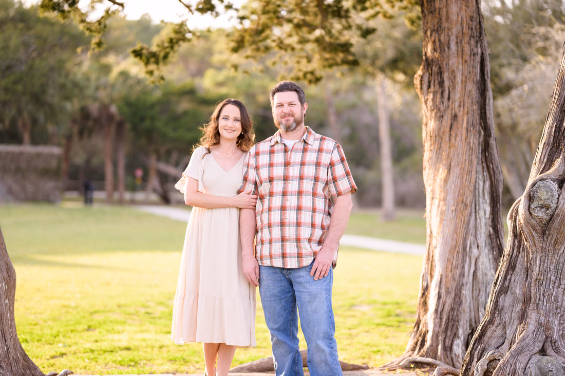 Couple standing under the old oak trees on the lawn near Atalaya Castle - Huntington Beach State Park