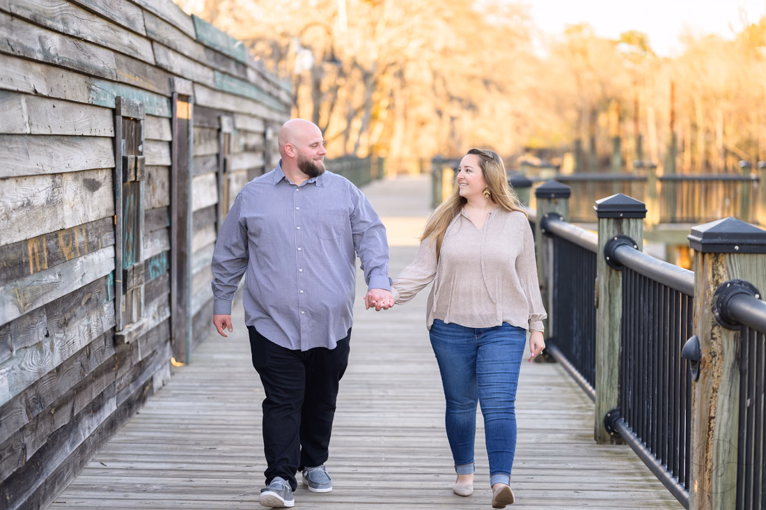 Couple walking hand in hand on the boardwalk by the river - Conway Riverwalk