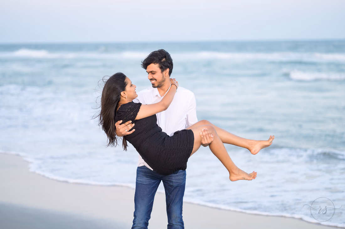 He carries her in his arms by the waves - Huntington Beach State Park