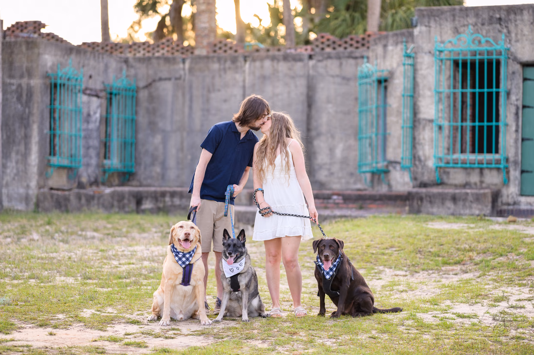 Couple kissing in front of Atalaya Castle with their three dogs - Huntington Beach State Park