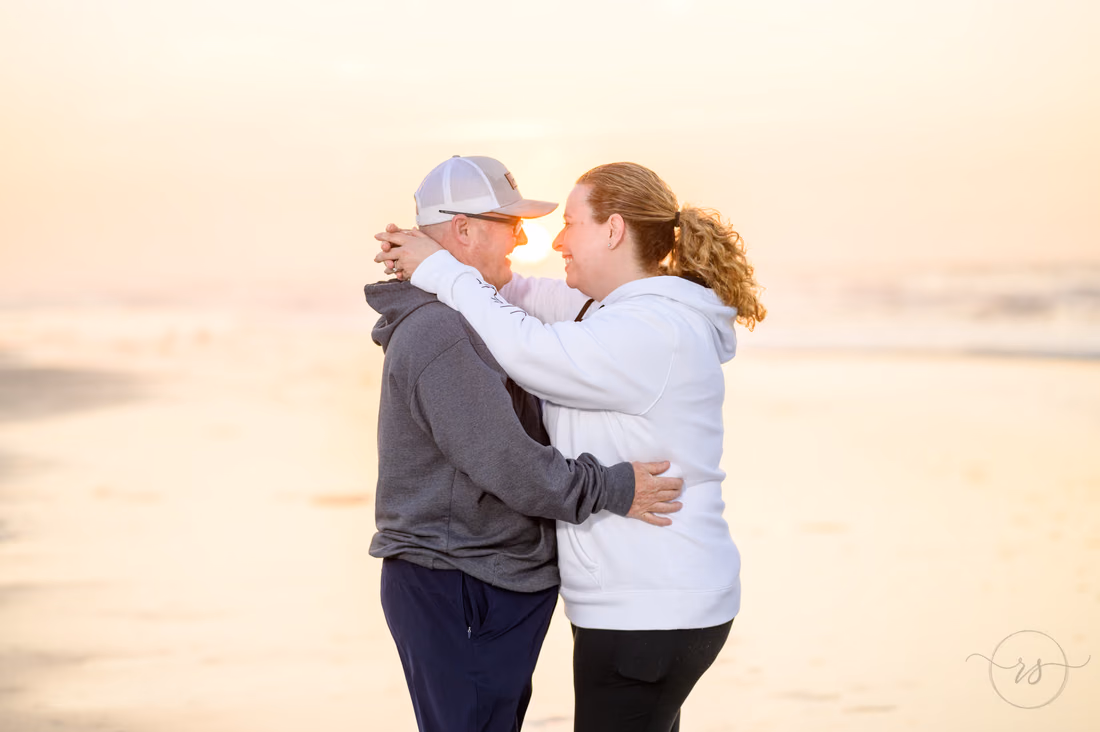 Older couple hugging on the beach in the soft sunrise light - Ocean Isle