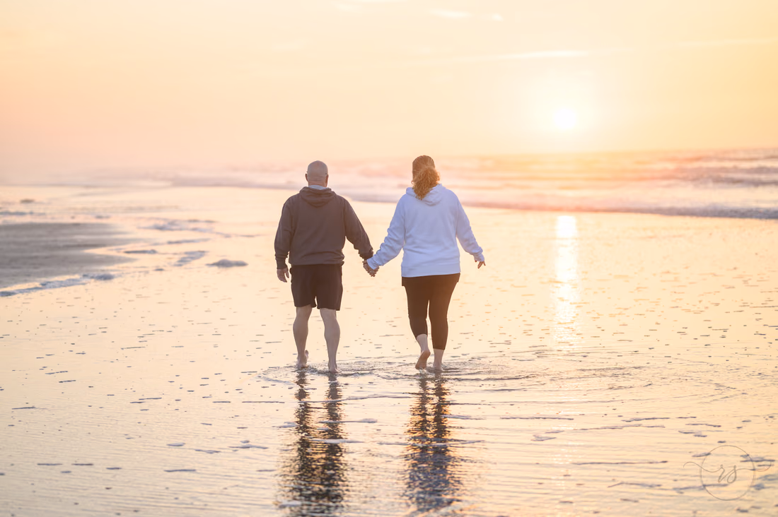 Older couple walking hand in hand into the sunrise - Ocean Isle