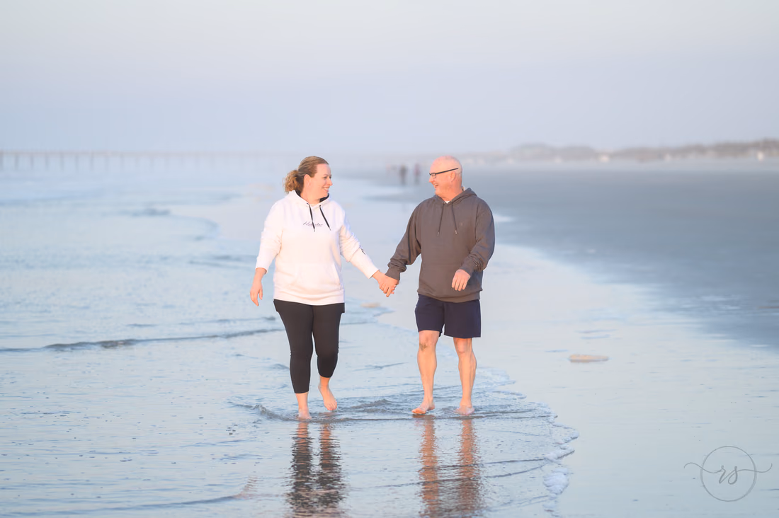 Older couple walking along the misty shoreline at sunrise - Ocean Isle